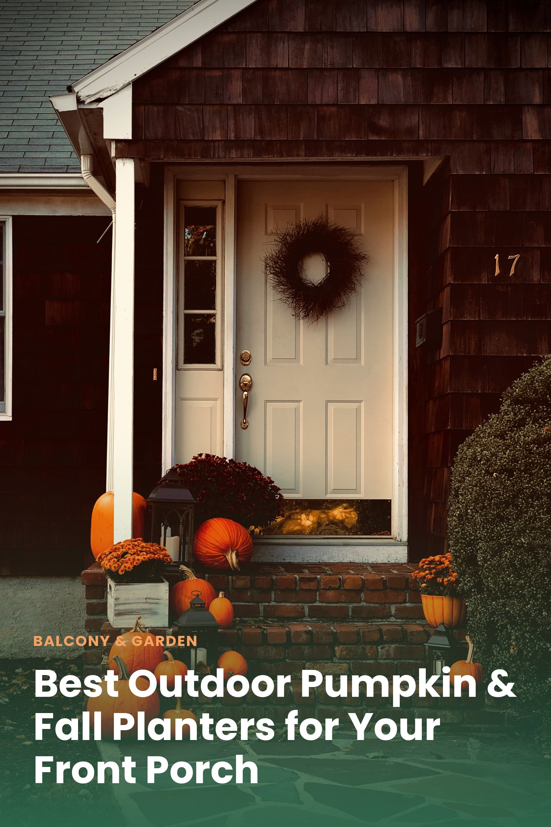 A front porch decorated with large fall planters filled with mums and pumpkins