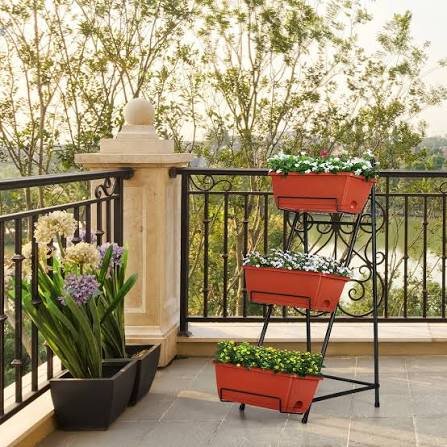 Brick-red metal 3-tier standing planter with stair-stepped boxes on a balcony railing
