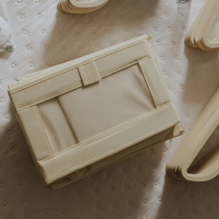 Cream fabric zippered storage box folded flat on a bed