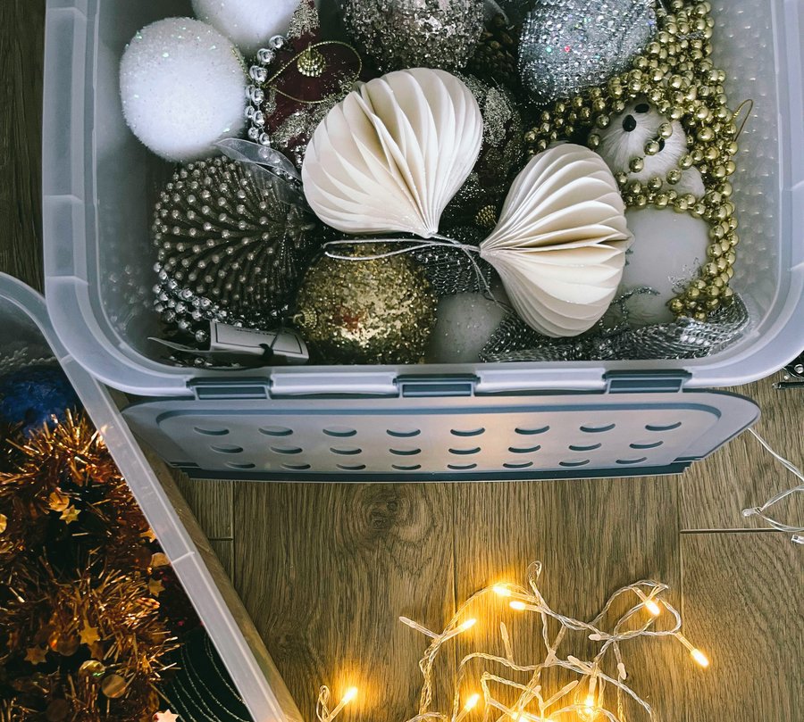 A clear plastic storage bin with a latching lid holding ornaments and garland, a stock photo that stands in for a holiday tote