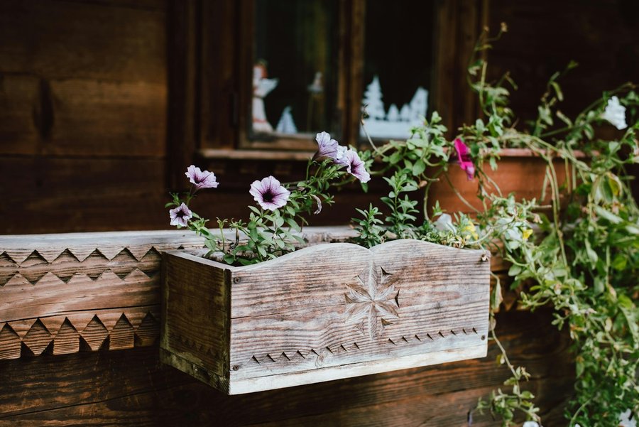 A rustic carved wooden planter box with flowers
