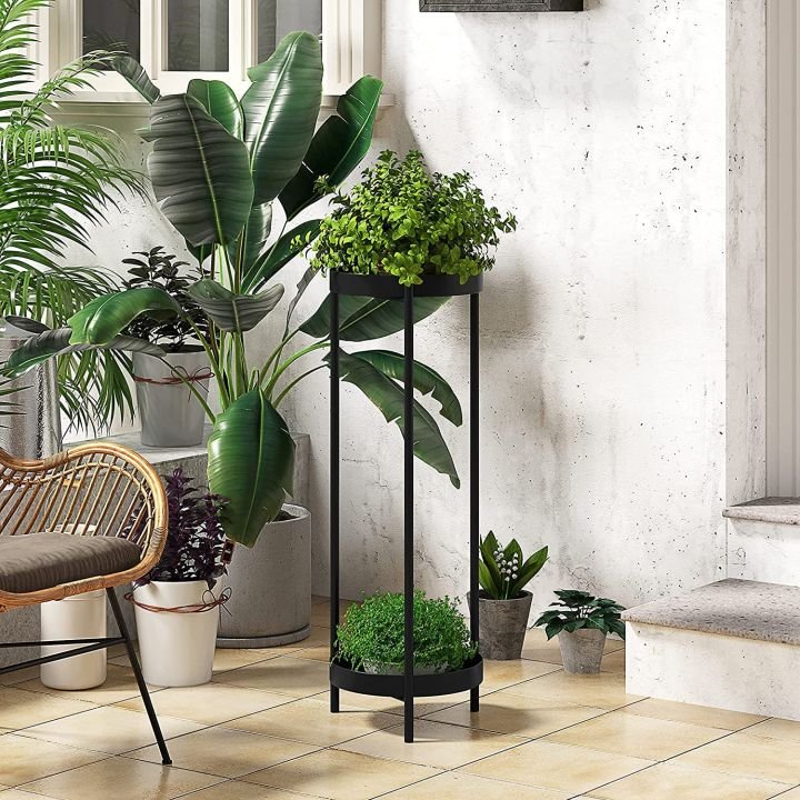 Black two-tier round metal plant stand with a slim profile, in a styled entryway